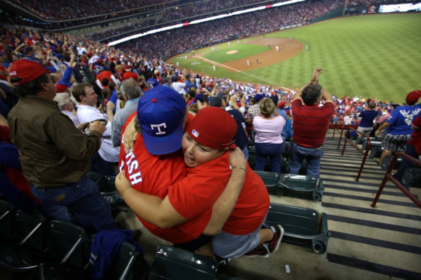 Eugene Fletcher hugged Colin McClellan, 11, after the Rangers' Nelson Cruz homered against...