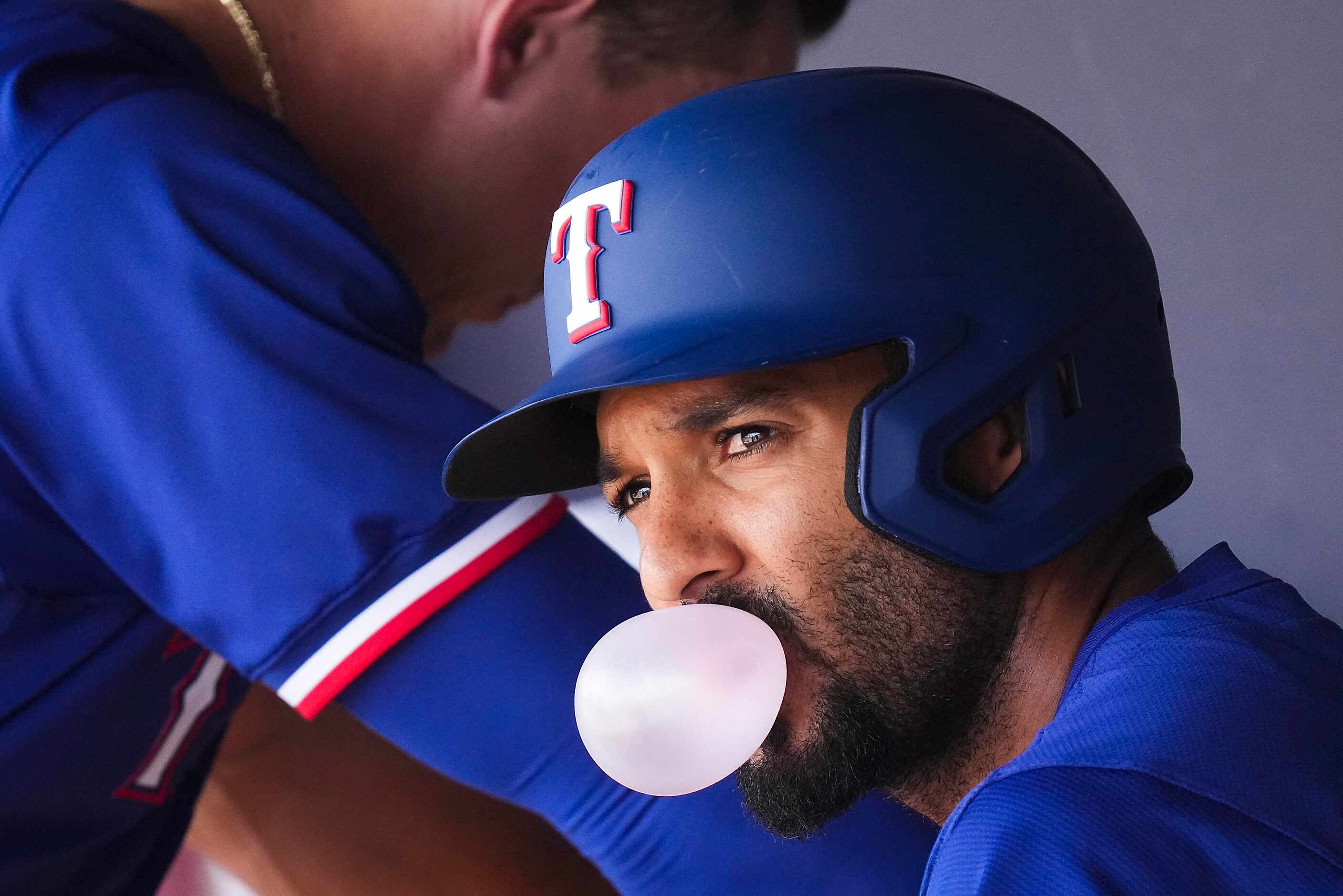 Texas Rangers infielder Marcus Semien blows a bubble in the dugout before a spring training...