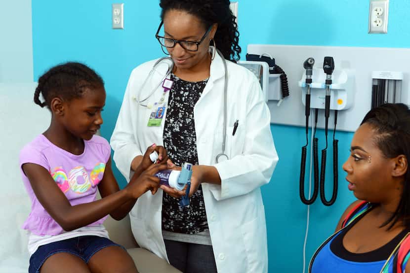 A young girl speaks with her primary care doctor in an exam room while her mother sits across.