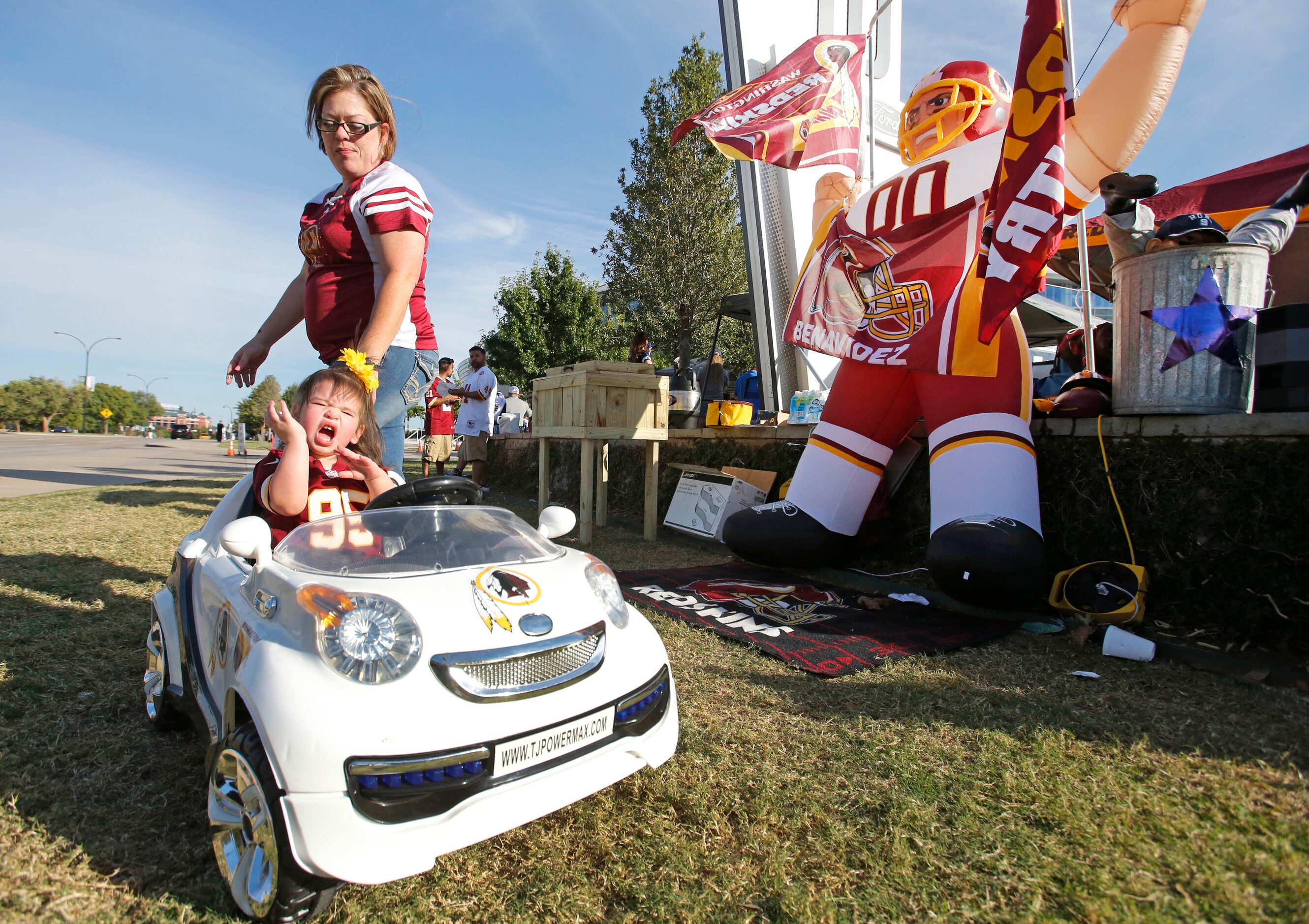 Chandler Benavidez (in car) comes ready to cheer on the Redskins from her toy car as she and...