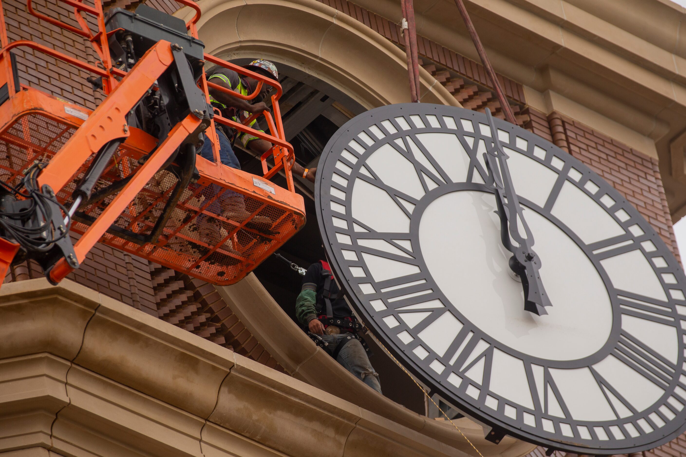 Workers from MEI Rigging & Crating work to install a 12-foot glass clock on the Grapevine...