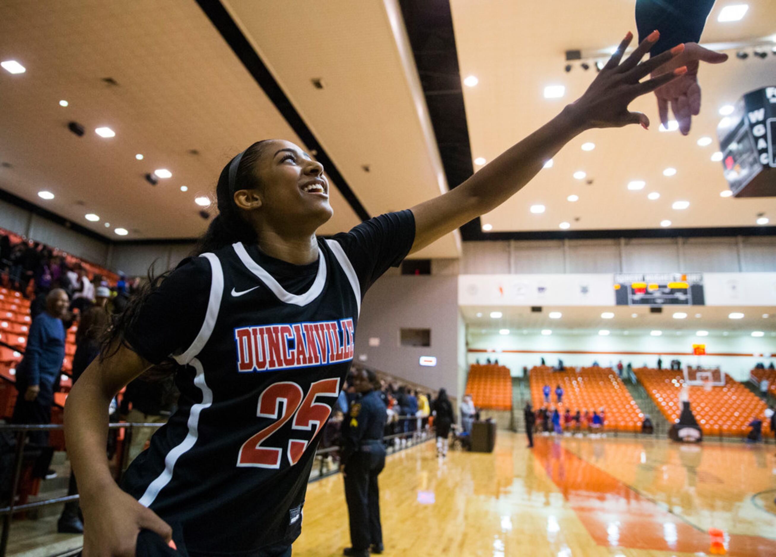 Duncanville's Deja Kelly (25) high-fives a fan as she exits the court after a 47-43 win in a...