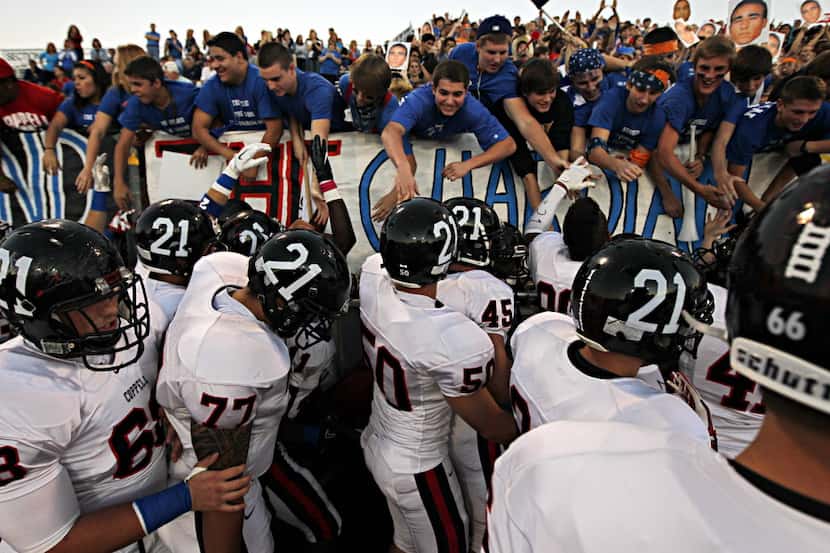 Wearing the number 21 on their helmets, the Coppell Cowboys varsity football team high fives...