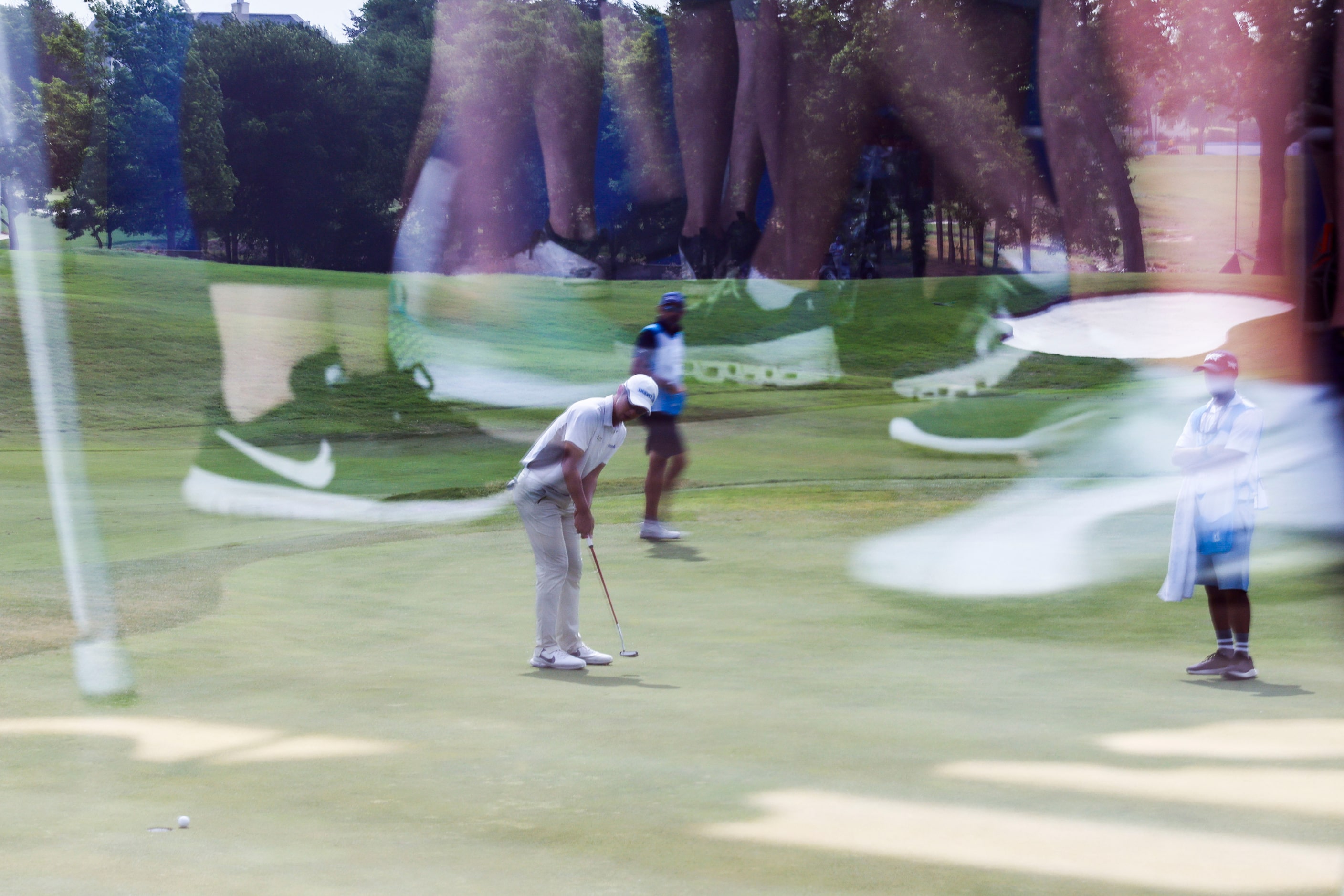 S.Y. Noh of South Korea is reflected on a glass window of a clubhouse as he putts on the...