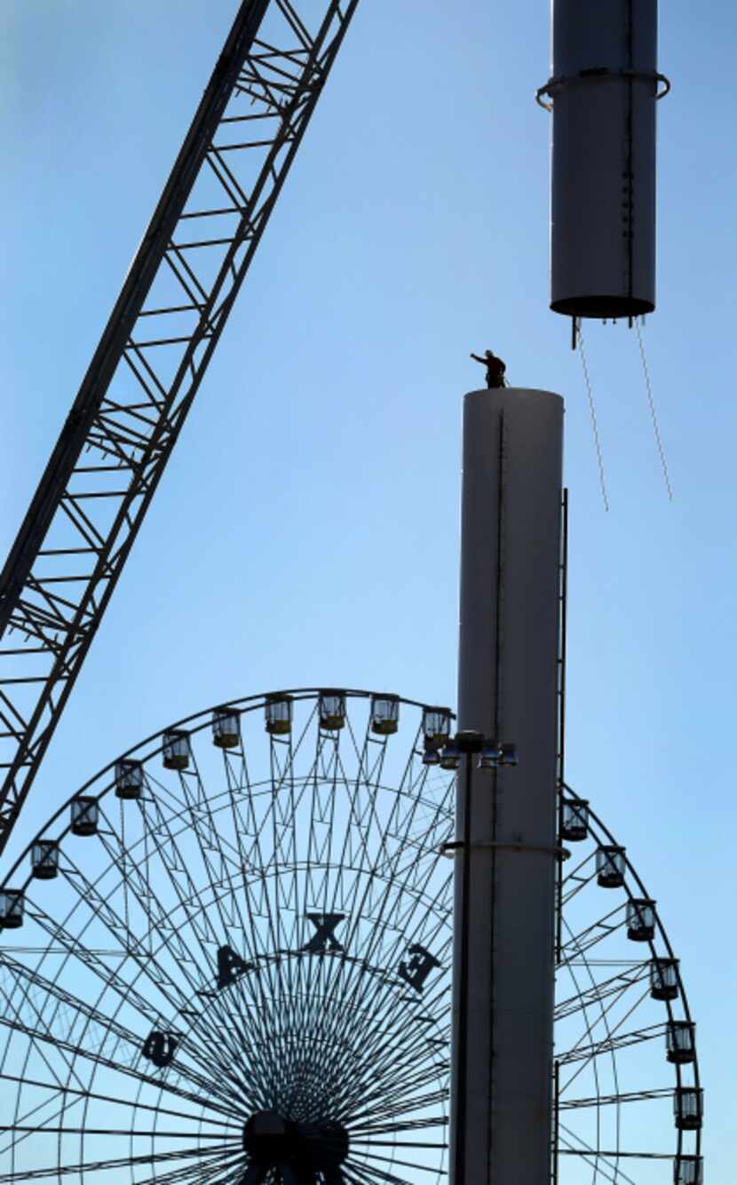 Workers guide the fourth section of the Top o' Texas Tower being installed at Fair Park.