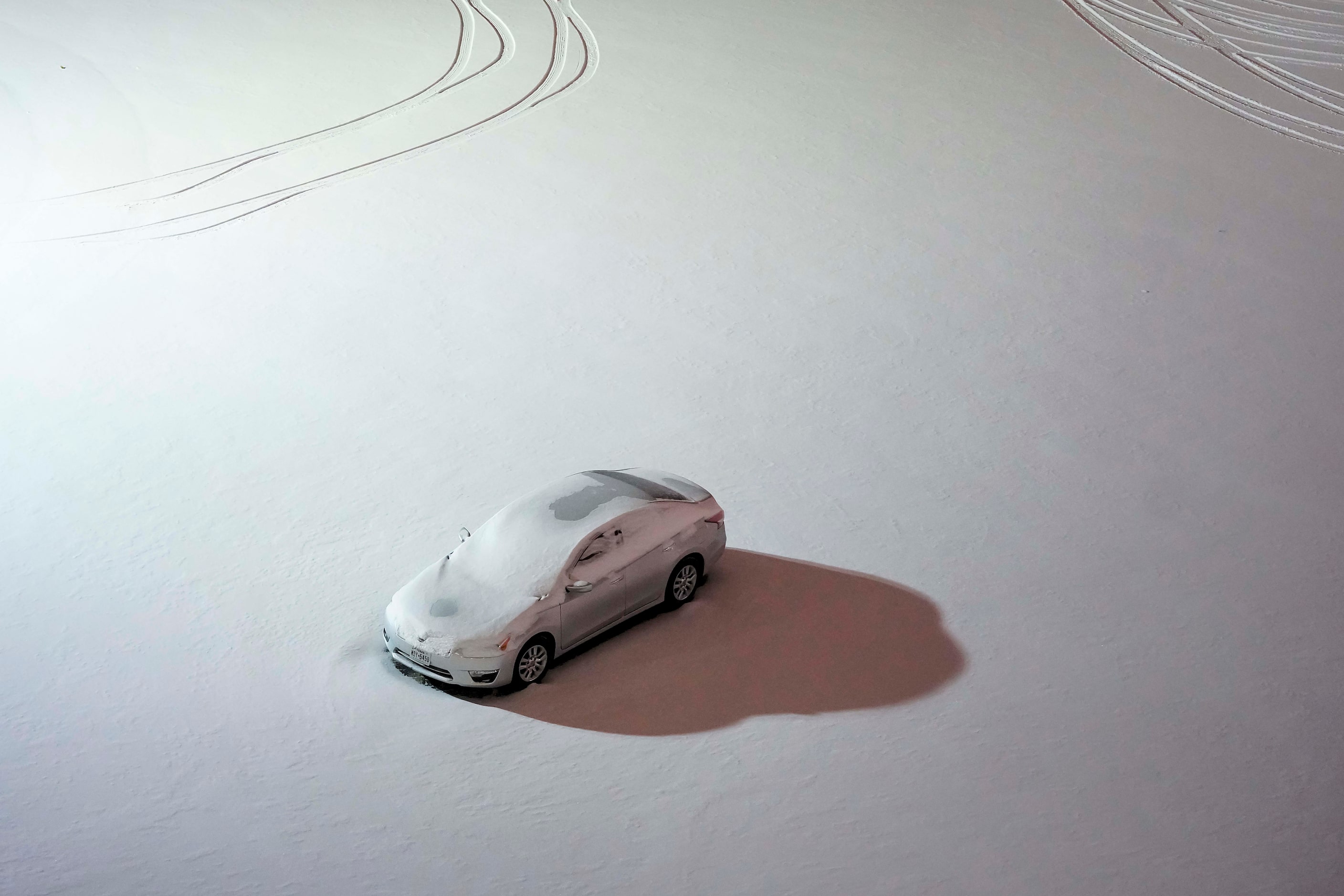 A lone car is covered in snow in a downtown parking lot as a winter storm brings snow and...