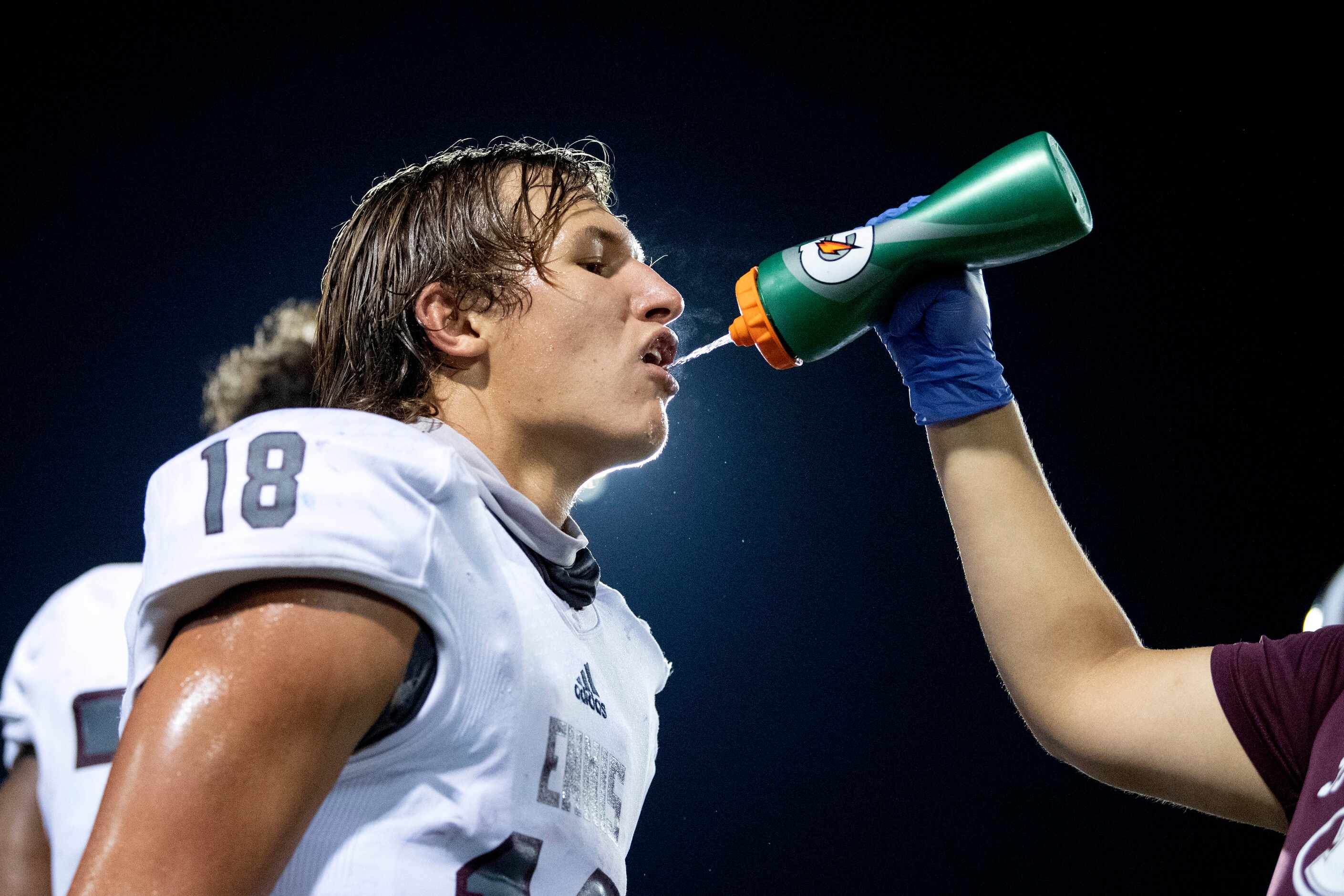 Ennis senior quarterback Collin Drake (18) gets a drink of water on the sidelines during the...