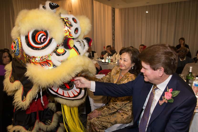 Grace McDermott watches as Arlington Mayor Jeff Williams feeds the lion a red envelope for...