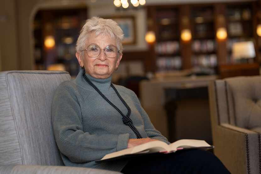 Woman sitting in a chair and reading a book in a library.