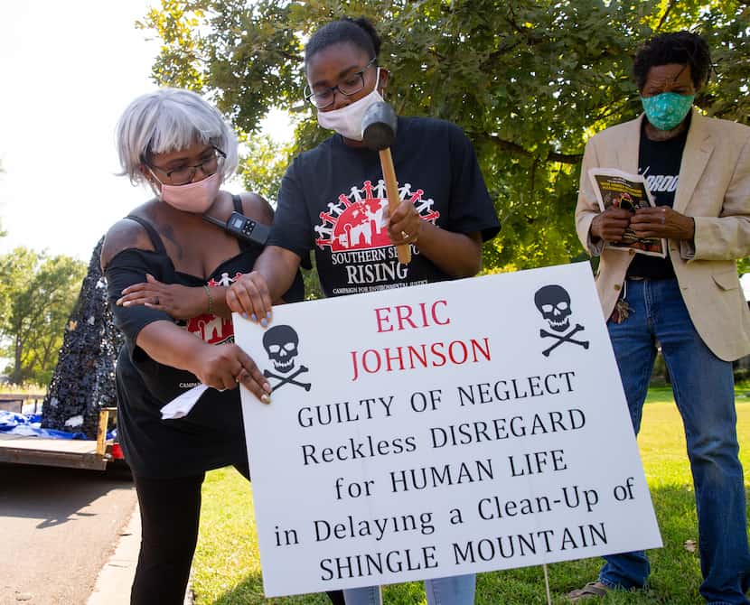 Oquinn (left) and demonstrator Essence Telteh place a sign near the home of Dallas Mayor...