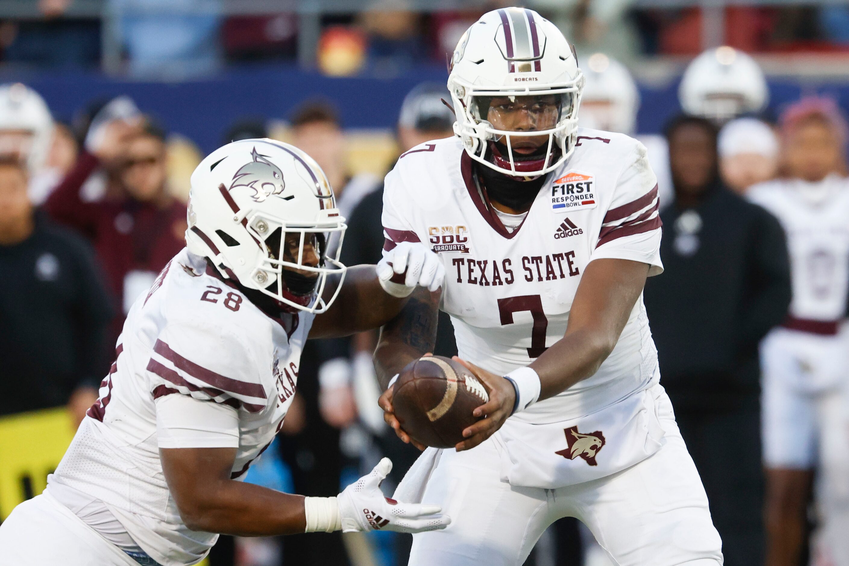 Texas State running back Jahmyl Jeter (left) takes the ball from Texas State quarterback TJ...