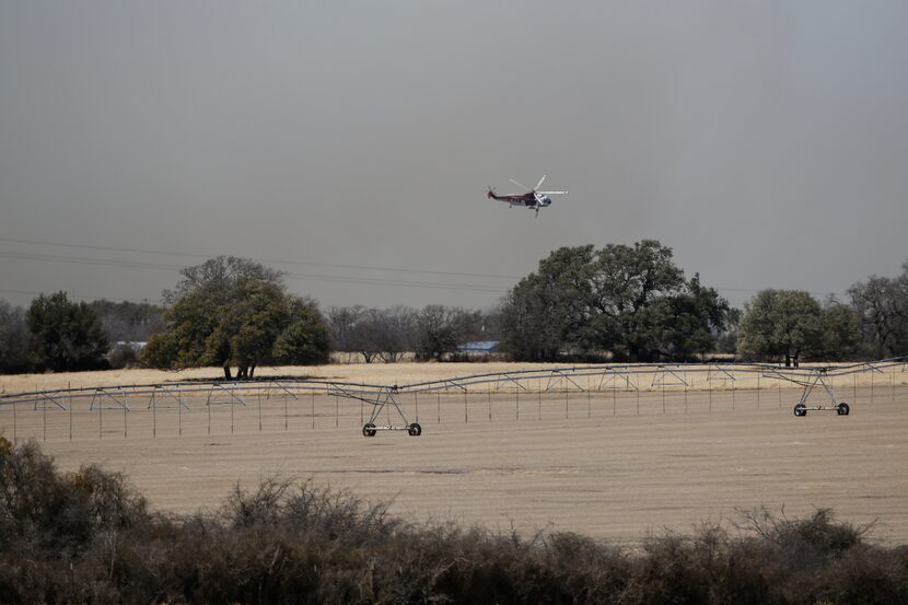 A helicopter flys out of smoke on Sunday, March, 20, 2022 near Eastland County in Texas. The...