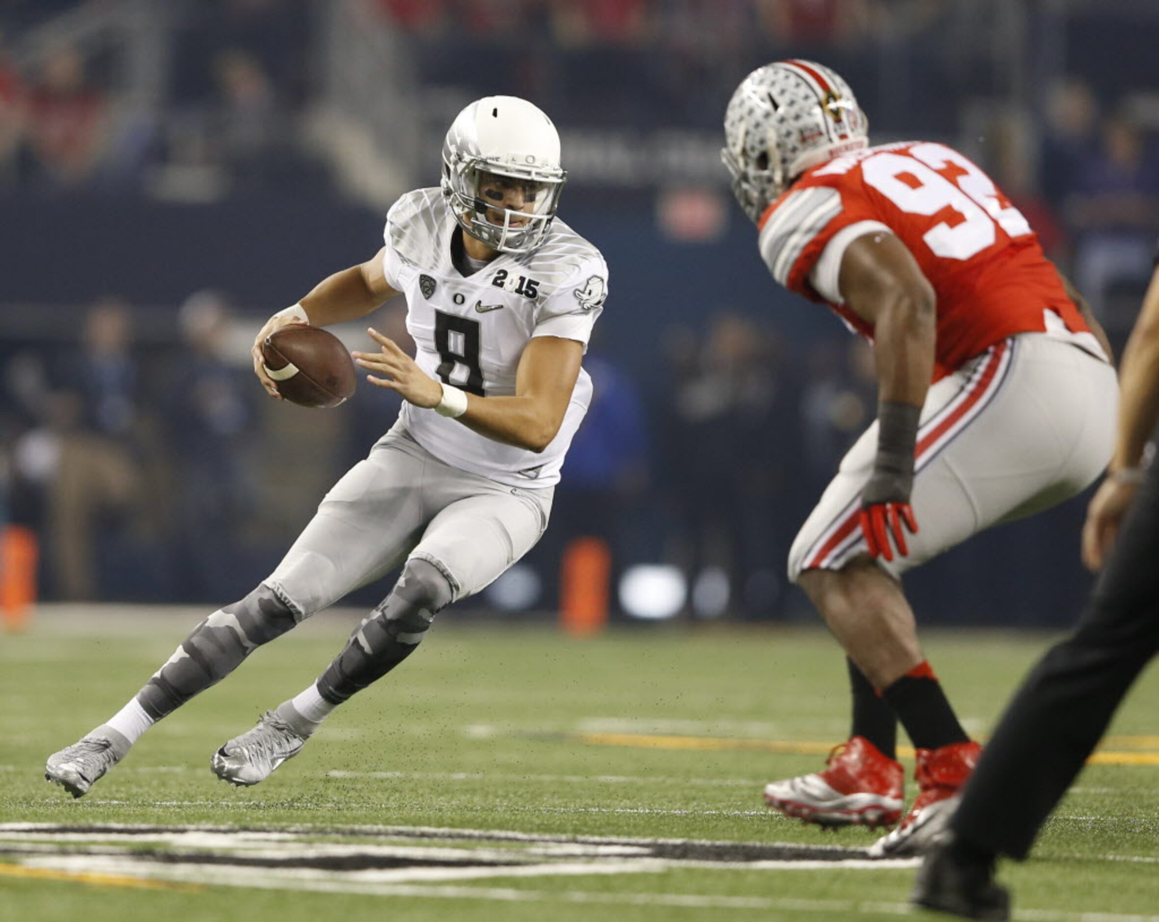 Oregon Ducks quarterback Marcus Mariota (8 tries to get past Ohio State Buckeyes defensive...