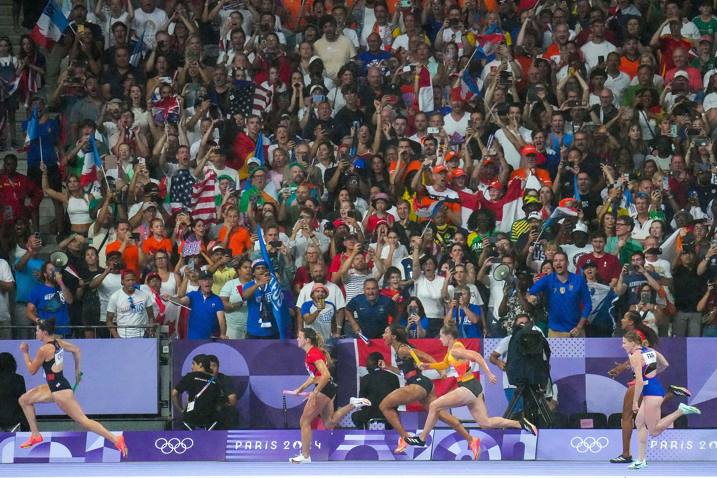 Fans cheer as runners round the track during the women’s 4x100-meter relay at the 2024...