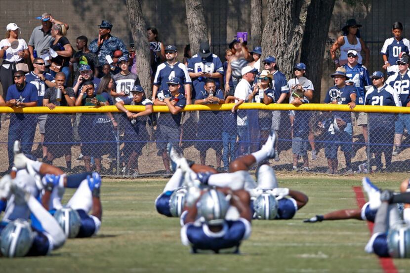 Dallas Cowboys fans watch the players during a warm-up at the training camp in Oxnard,...
