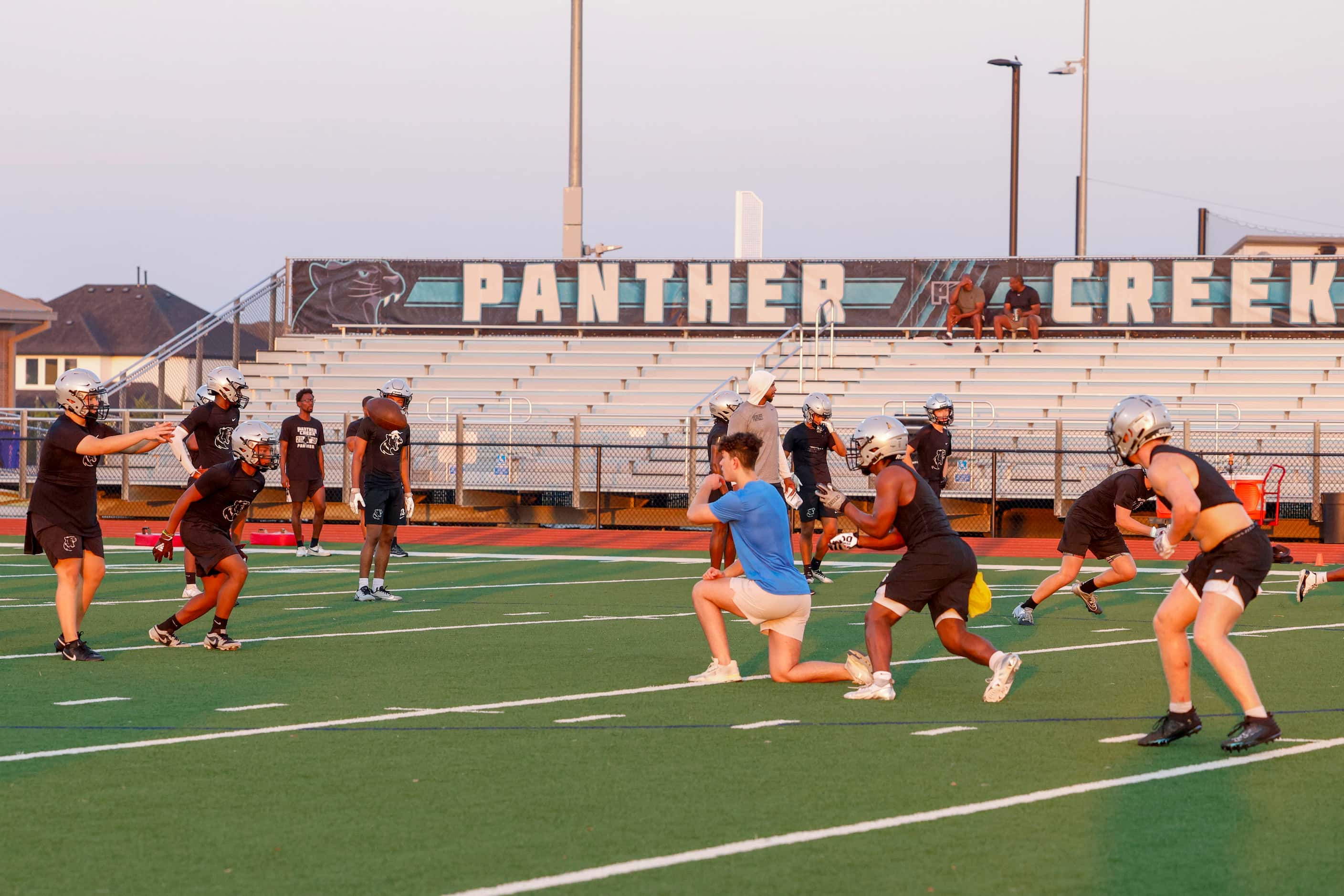 Football players run a play during an early morning practice at Panther Creek High School,...