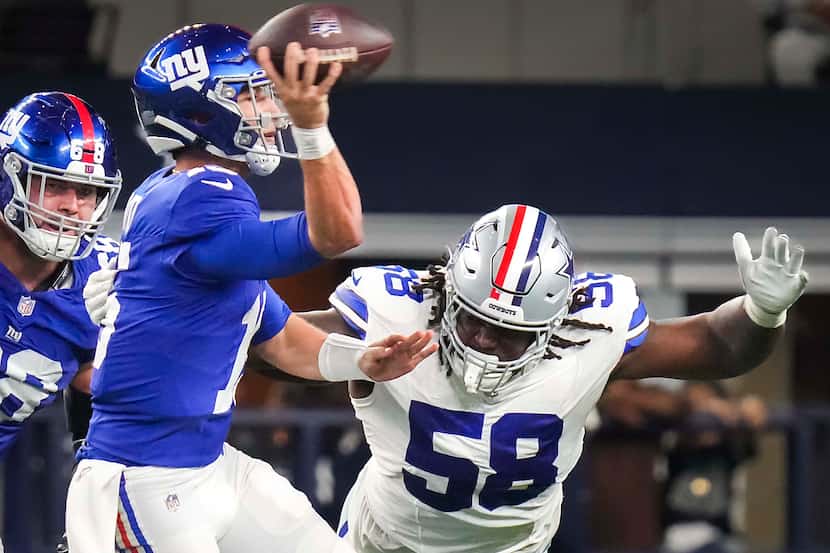 New York Giants quarterback Tommy DeVito (15) throws a pass under pressure from Dallas...