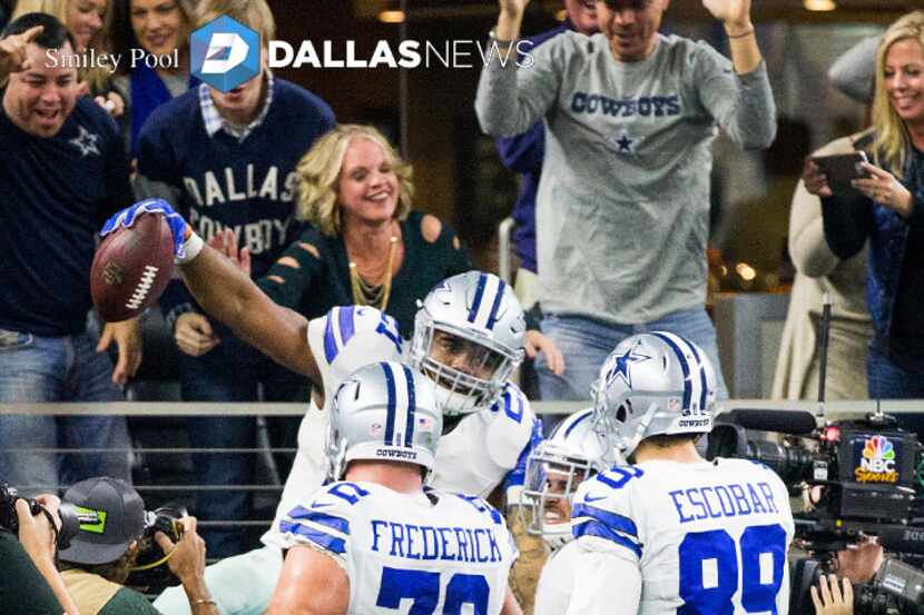 Dallas Cowboys running back Ezekiel Elliott (21) celebrates by jumping into and out of a...