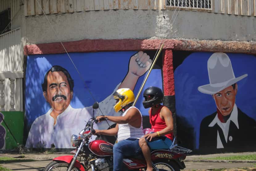 Un motociclista pasa frente a un mural del presidente de Nicaragua Daniel Ortega, izquierda,...