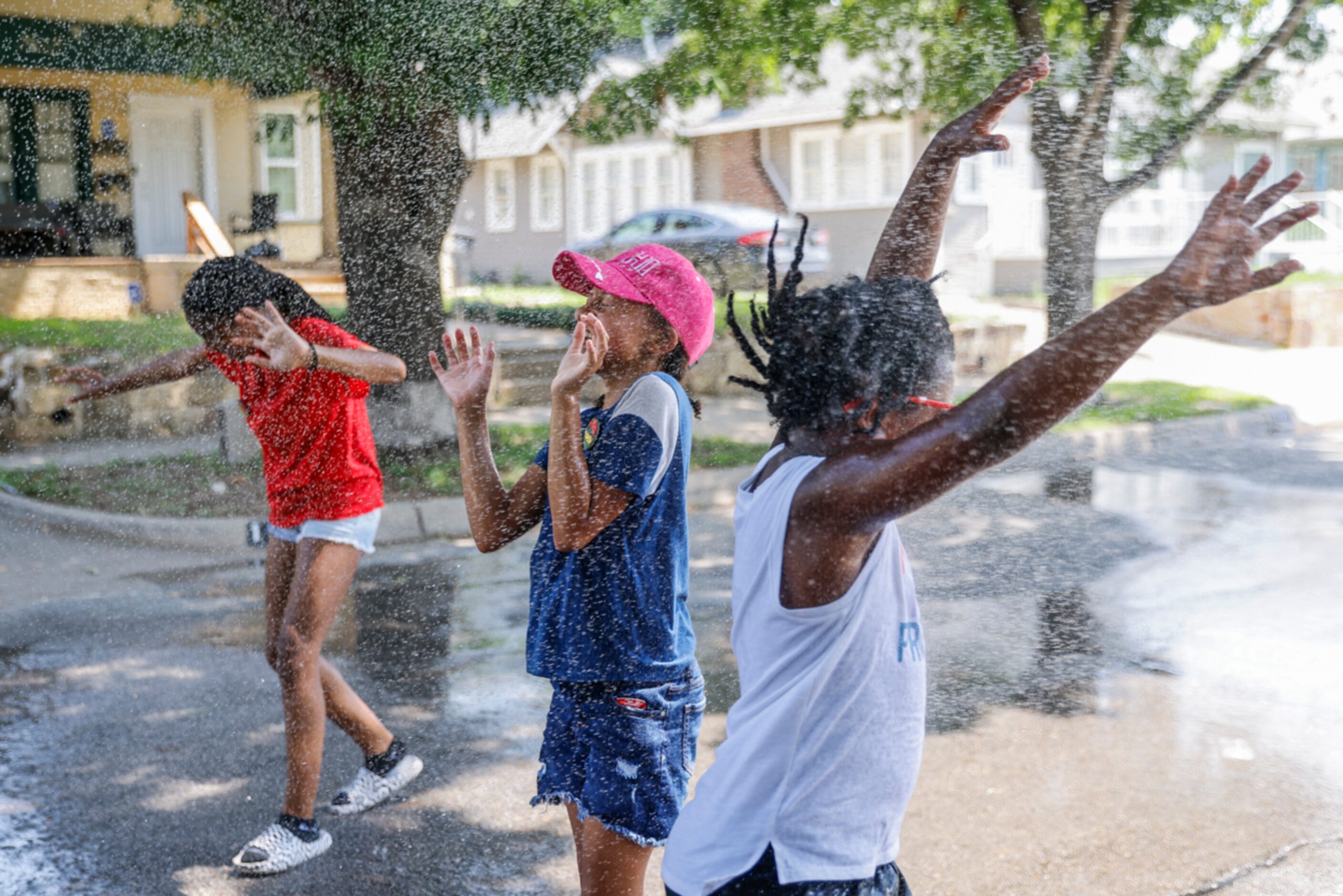 Evette Stone, 9, (center), and Lena Lee, 5, (left) enjoy their time as they cool off under a...