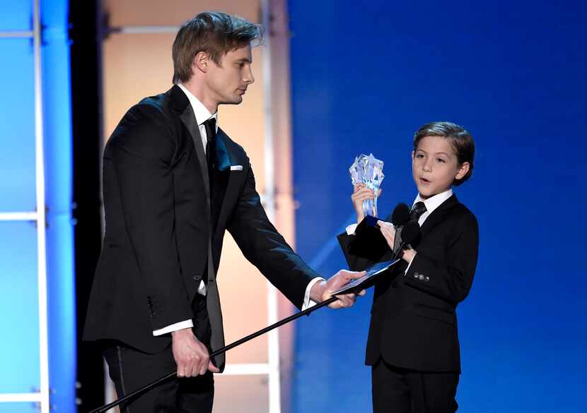 Bradley James, left, holds the microphone for Jacob Tremblay as he accepts the award for...