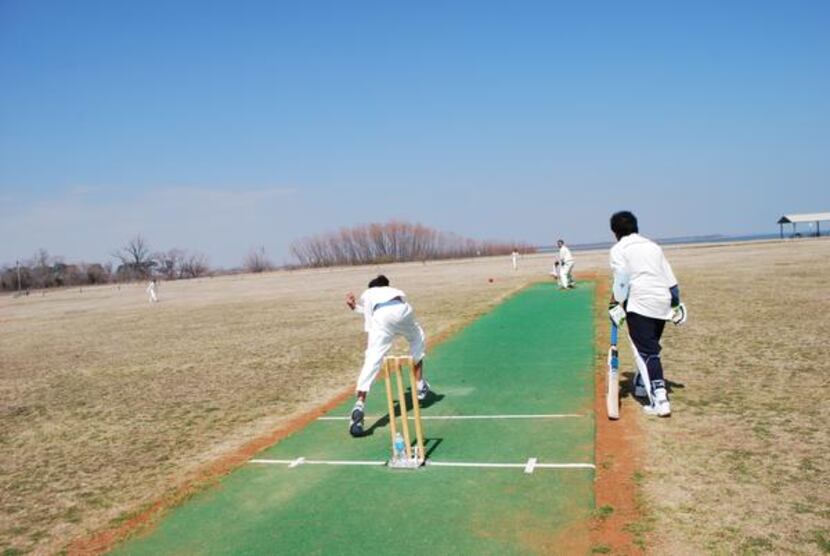 Ayush Todi (left) bowls to an adult batsman at a cricket match between the advanced members...