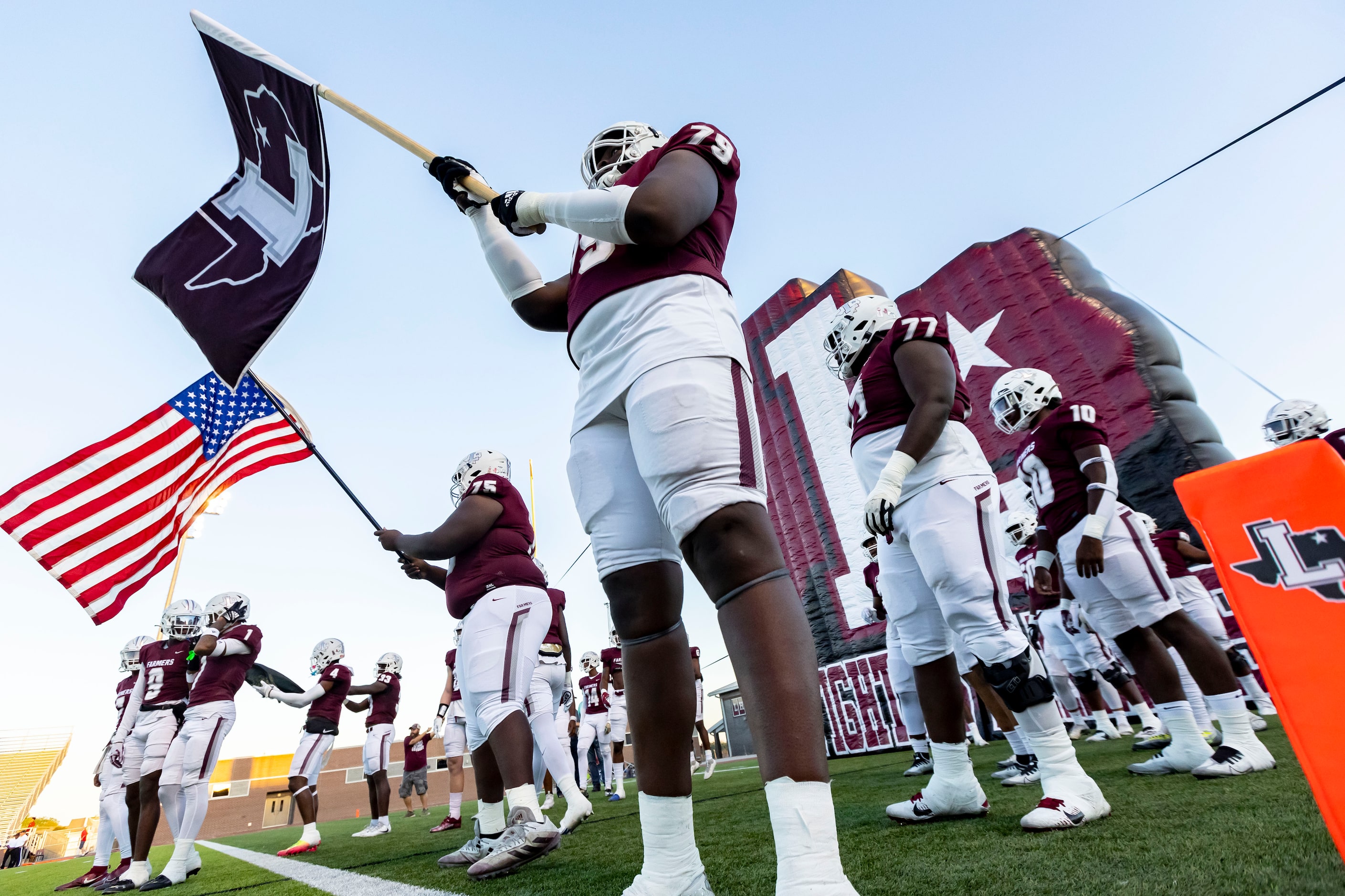 Lewisville senior offensive lineman Quaveon Davis (79) carries the school flag before the...