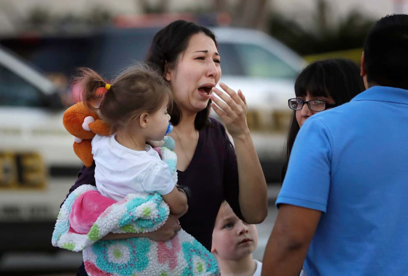 A woman holds her child after San Antonio police helped her and other shoppers exit the...