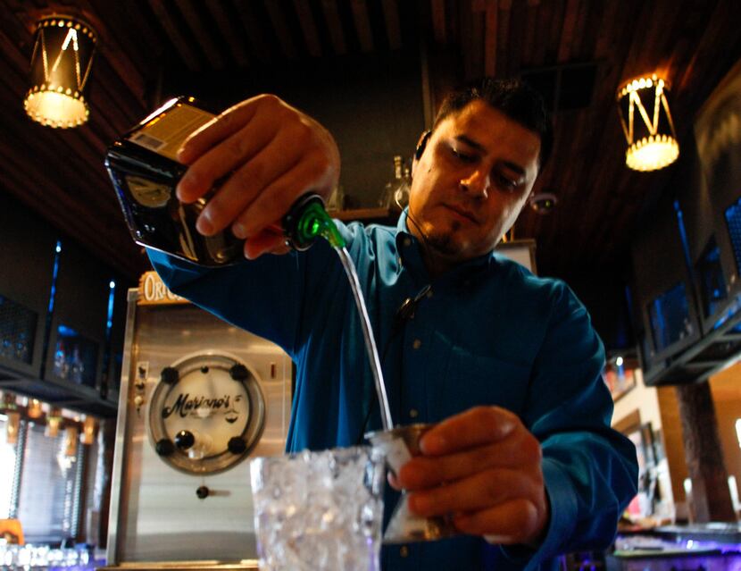 Head bartender Odie Martinez pours orange liqueur while making The Mariano margarita at...