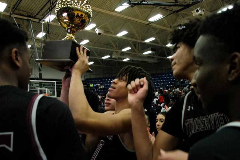 Mansfield Timberview players gather at mid-court as Joey Madimba raises the trophy after...