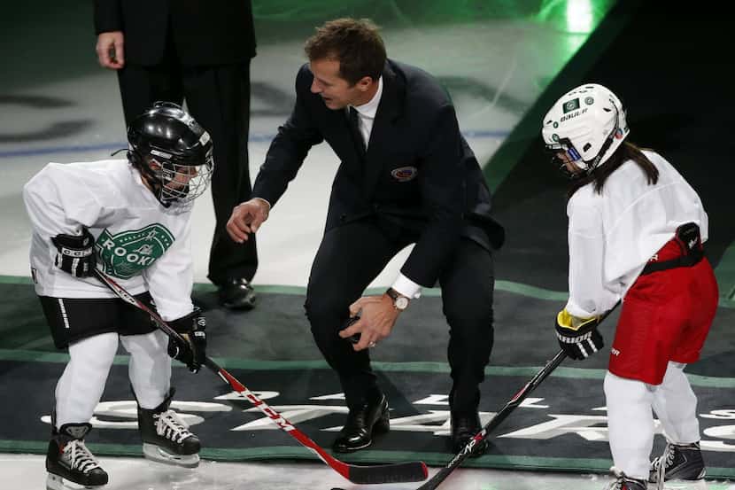 Former Dallas Stars players Mike Modano speaks to children before a ceremonial puck drop...