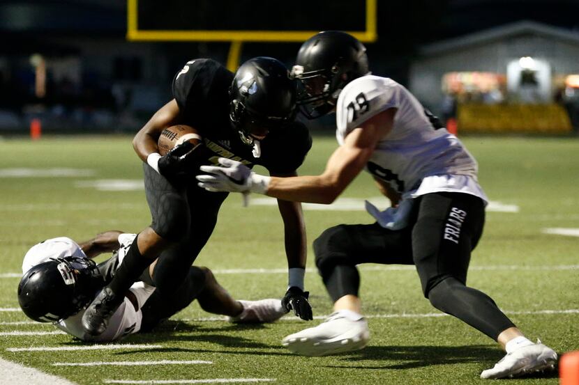 Kaufman's Casey Smith (12) is tackled by Bishop Lynch's Jeremy Irving (29) and Charles...
