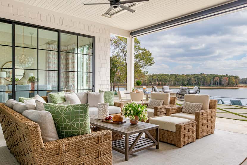 Covered patio at a lakefront home, with an outdoor sofa and coffee table, white flowers, and...
