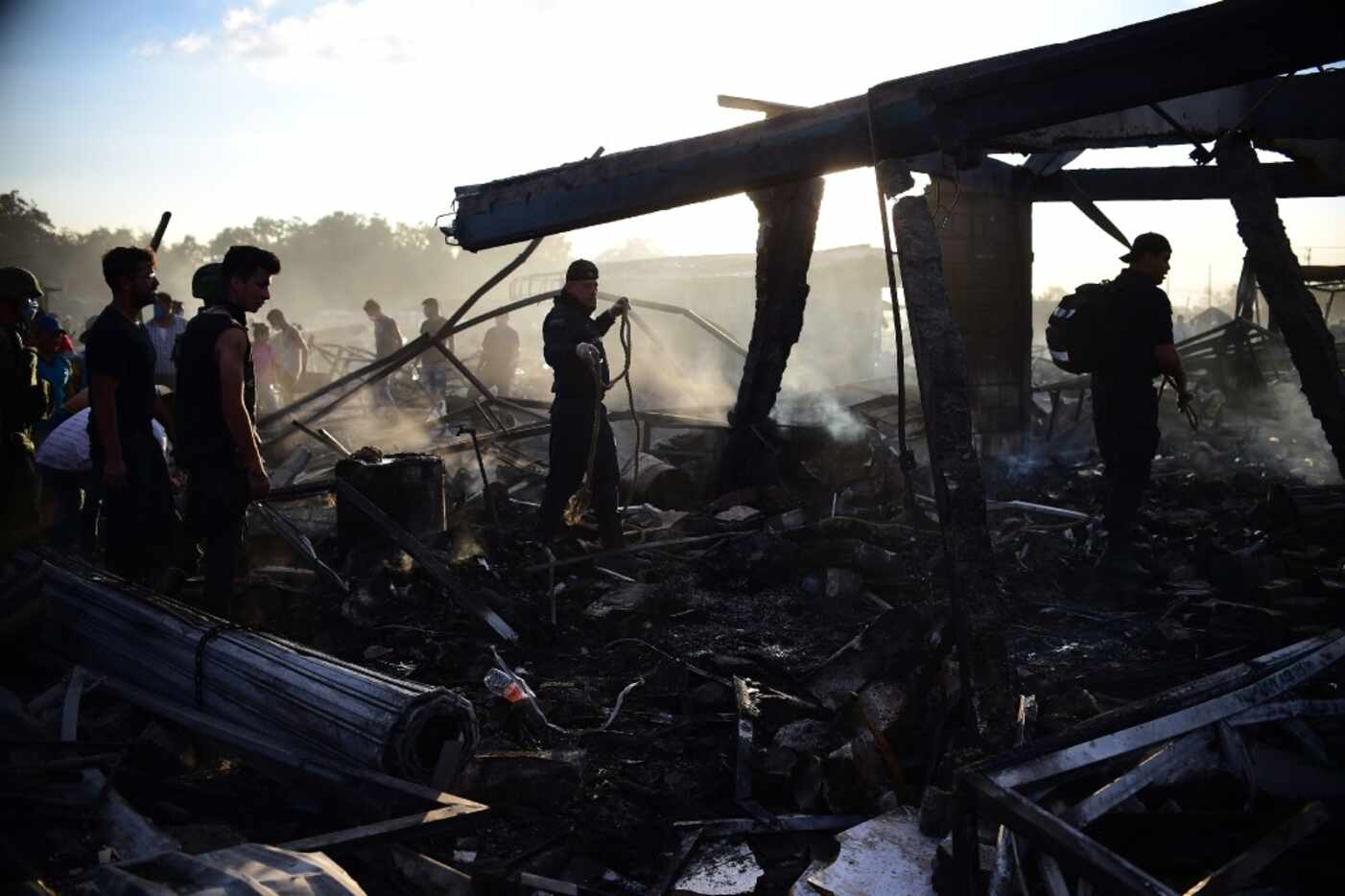 Firefighters, rescuers and survivors search amid the debris left by a huge blast that...