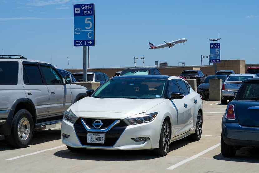 An American Airlines flight takes off over cars parked on the rooftop level of the terminal...
