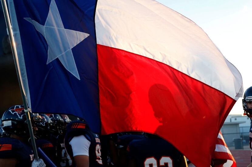 Sachse players were silhouetted in the Texas flag before entering the field before the first...