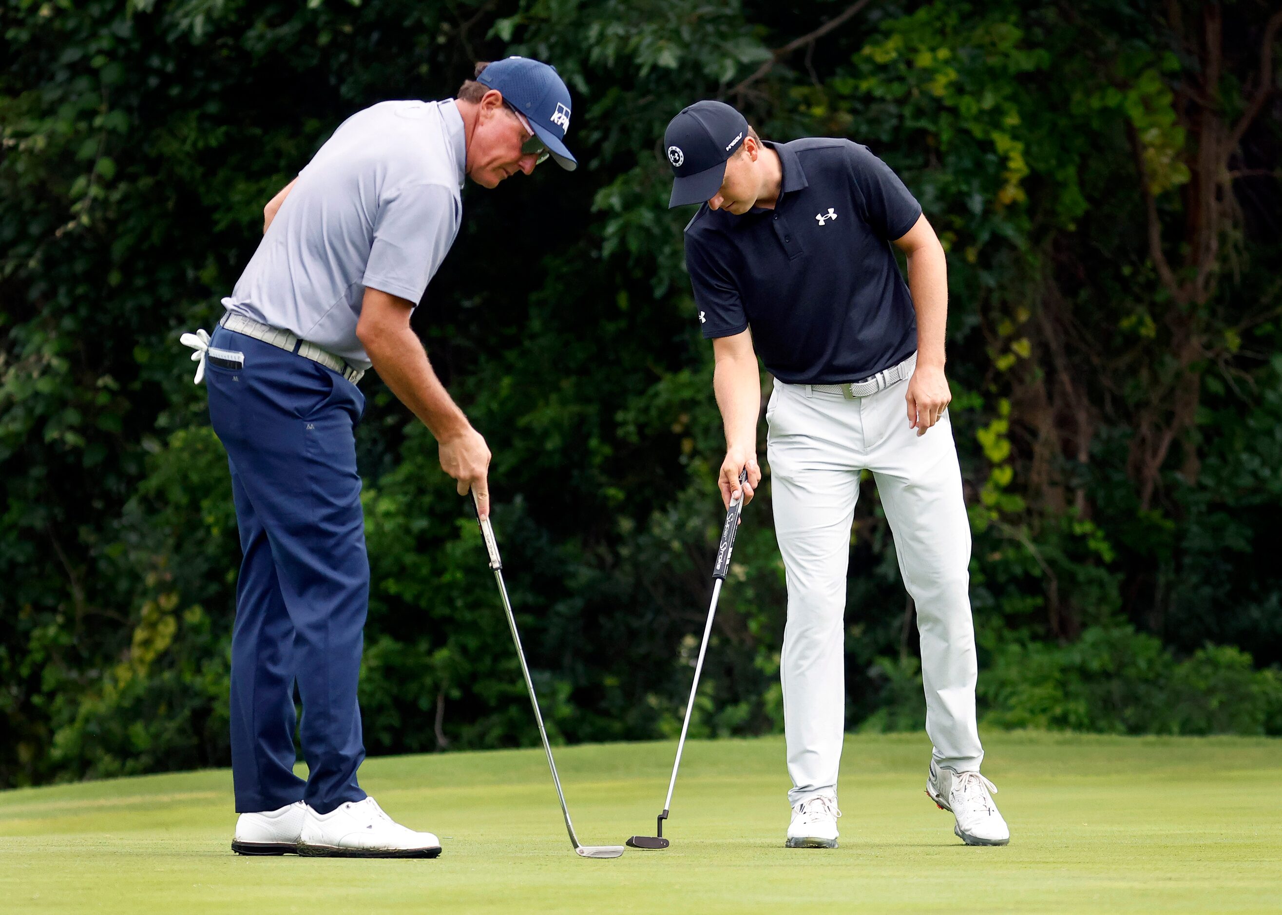 Professional golfers  Phil Mickelson (left) and Jordan Spieth tap down the putting surface....