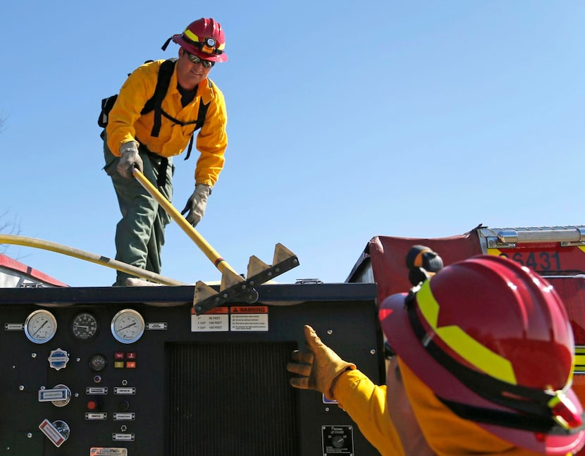 
Plano Fire-Rescue's Kade Wallace hands a fire rake to Mark Hardy in preparation for a...