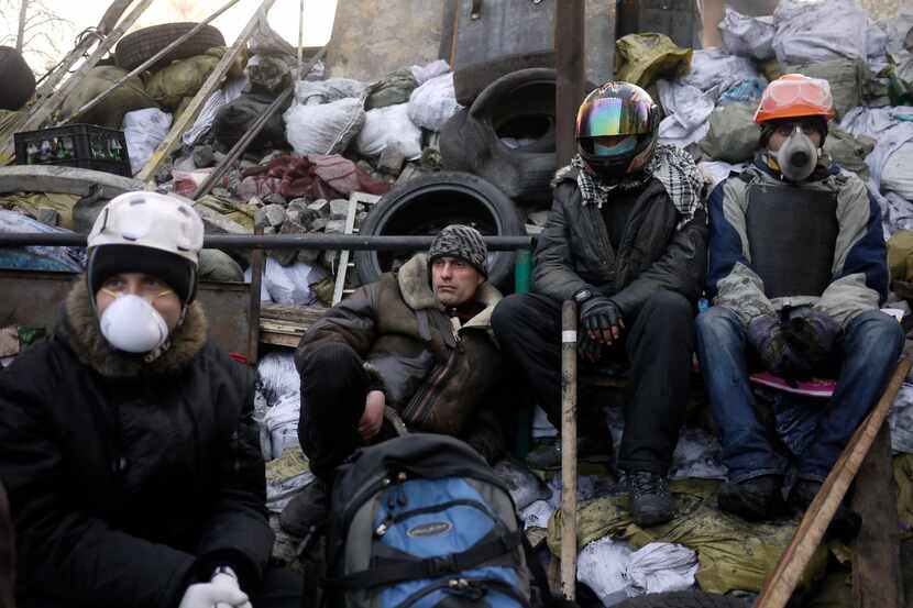 Anti-government protesters take a break on a barricade at Independence Square in Kiev,...