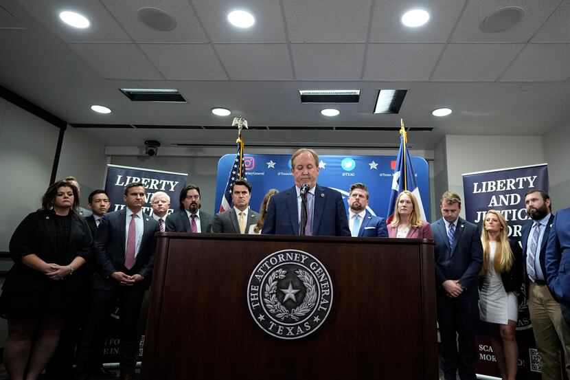 Texas state Attorney General Ken Paxton, center, flanked by his staff, reads a statement at...