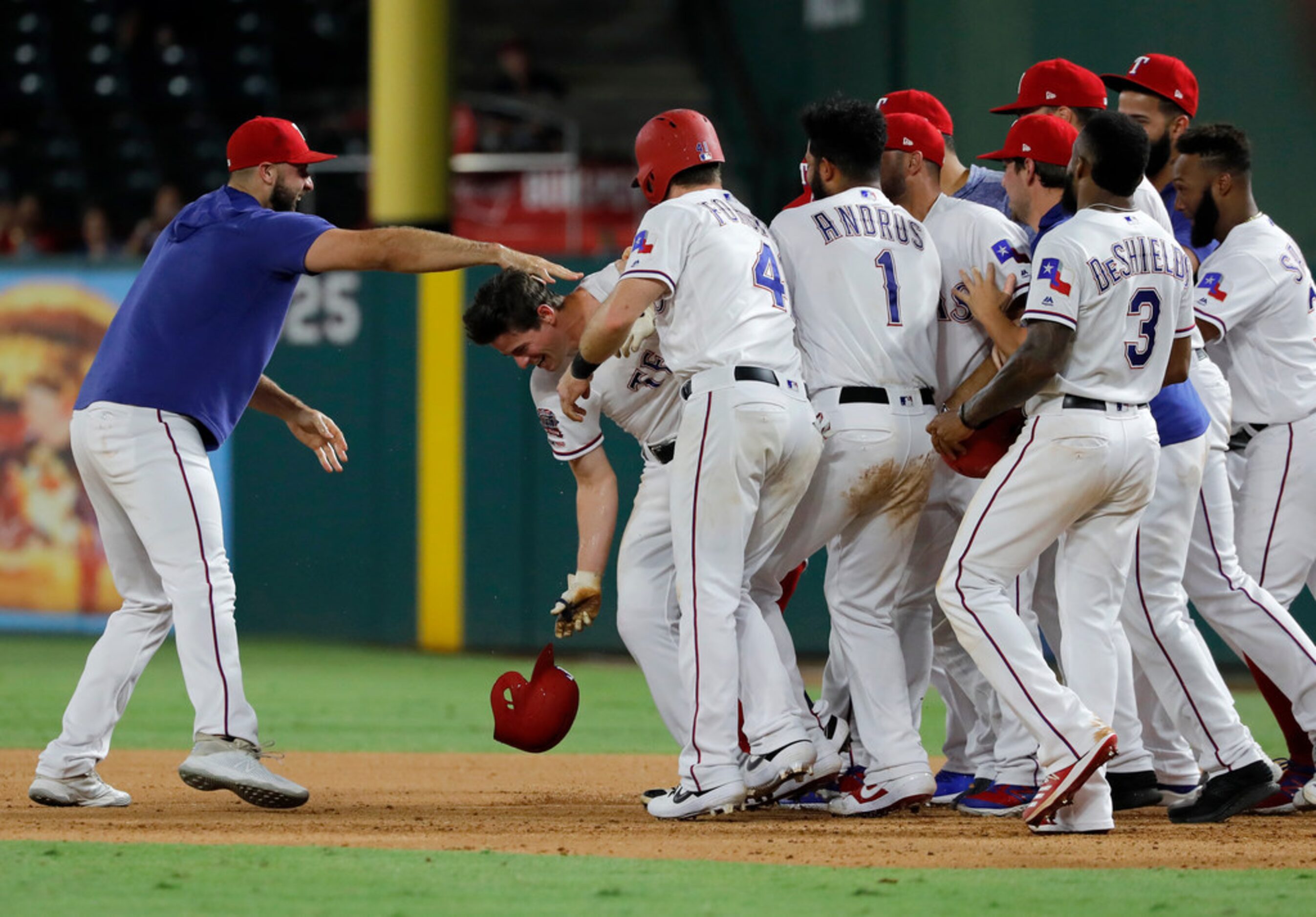 Texas Rangers' Nomar Mazara, left, and teammates mob Nick Solak, second from left dropping...