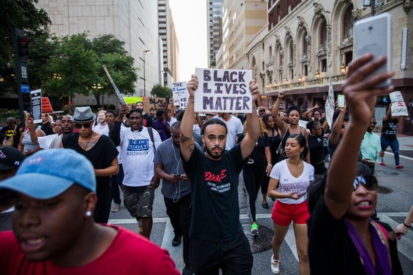 Protesters march through downtown Thursday before a gunman later identified as Micah X....