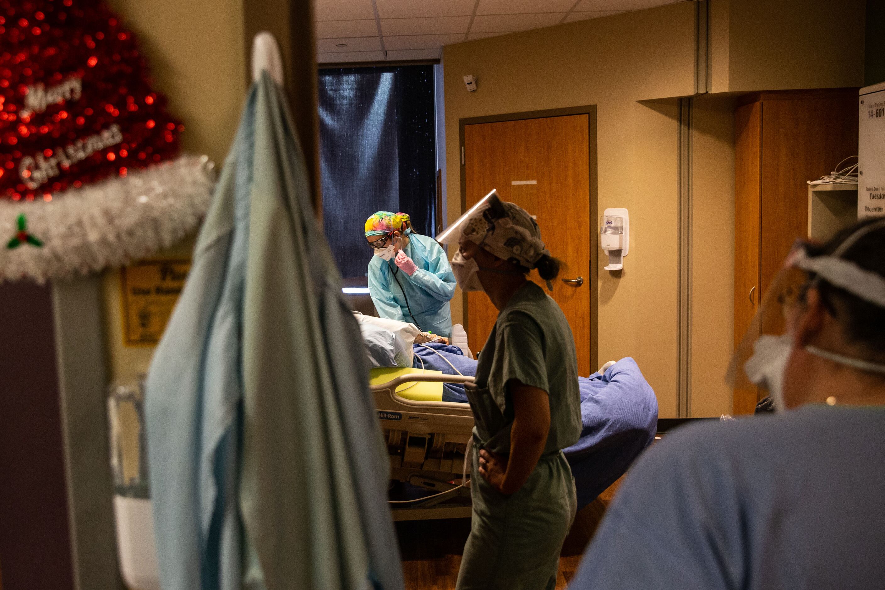 Rowley (right) checks in as nurse Allison Hurley monitors a COVID-19 patient’s declining...