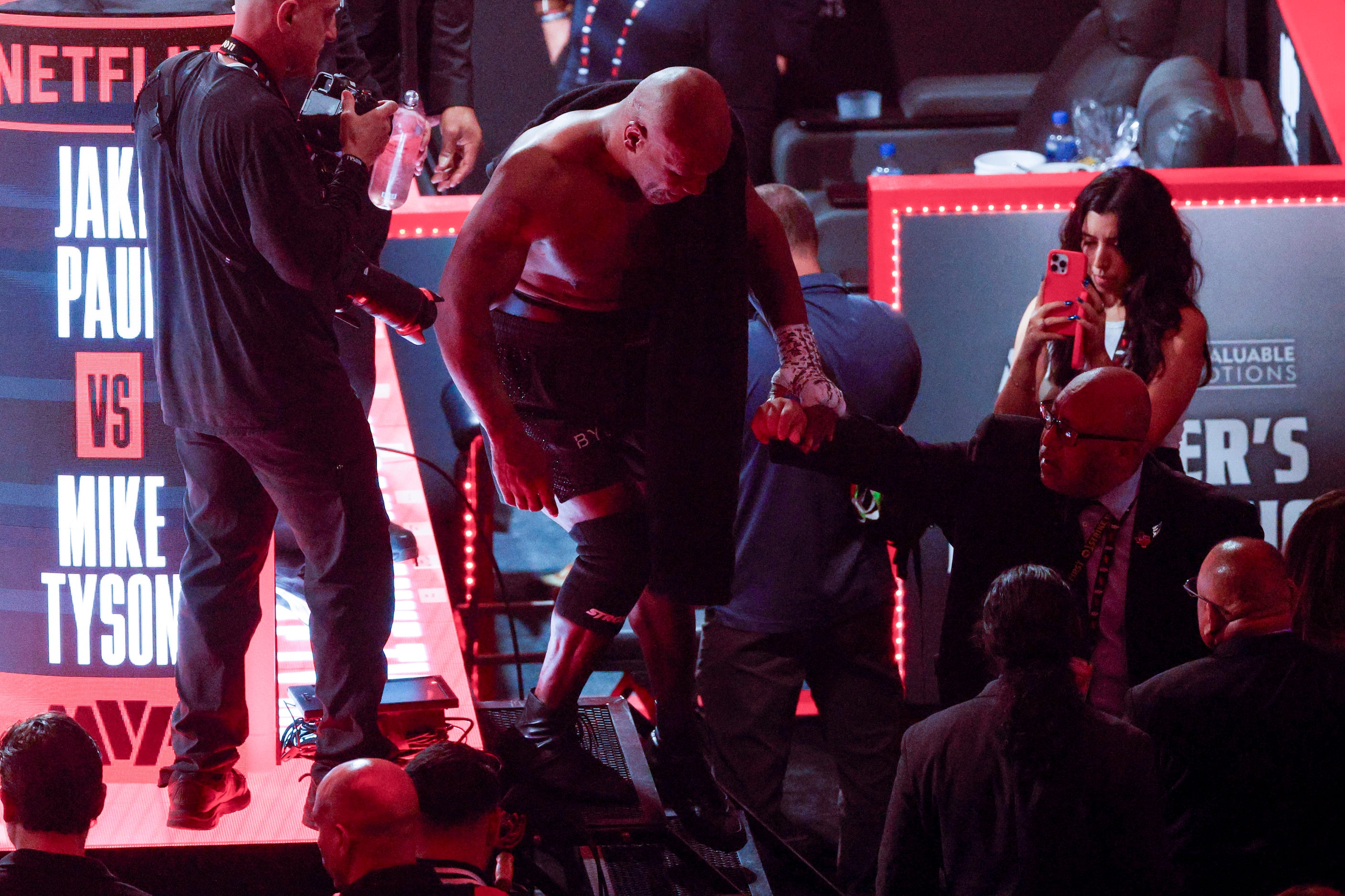 Mike Tyson is helped out of the ring after a heavyweight boxing match against Jake Paul,...