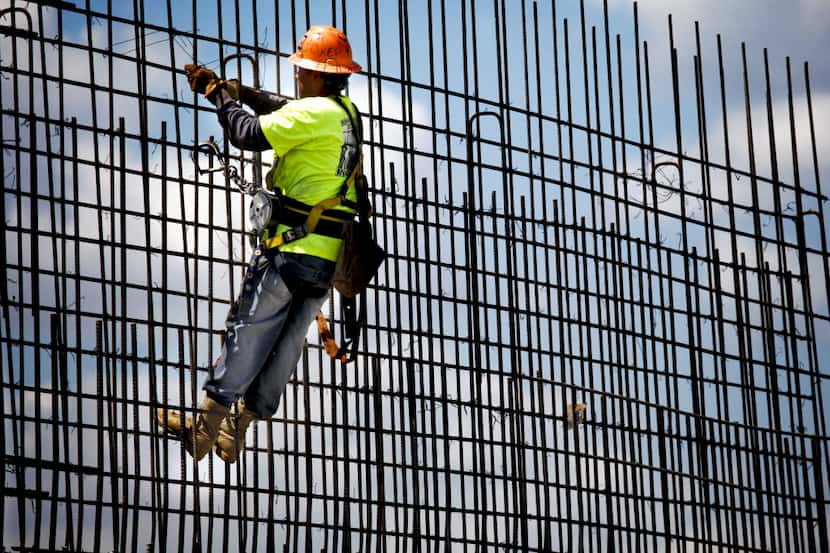 Texas Sterling Construction worker, Omar Gonzalez, secures a grid of reinforcing bar, or...