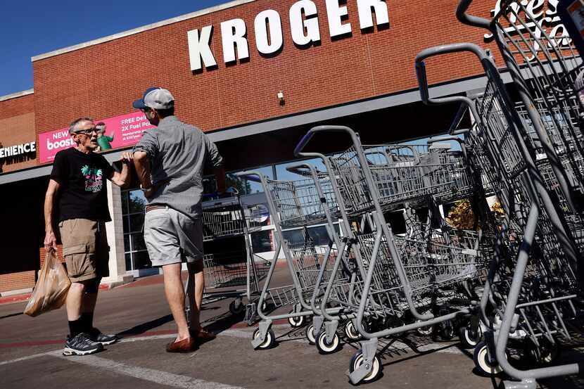 Shopper Jimmy Bartlett of Dallas (left) visits with a friend outside the Kroger grocery...