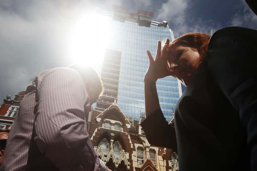 A woman shields her eyes as sunlight is reflected off the so-called Walkie Talkie building...