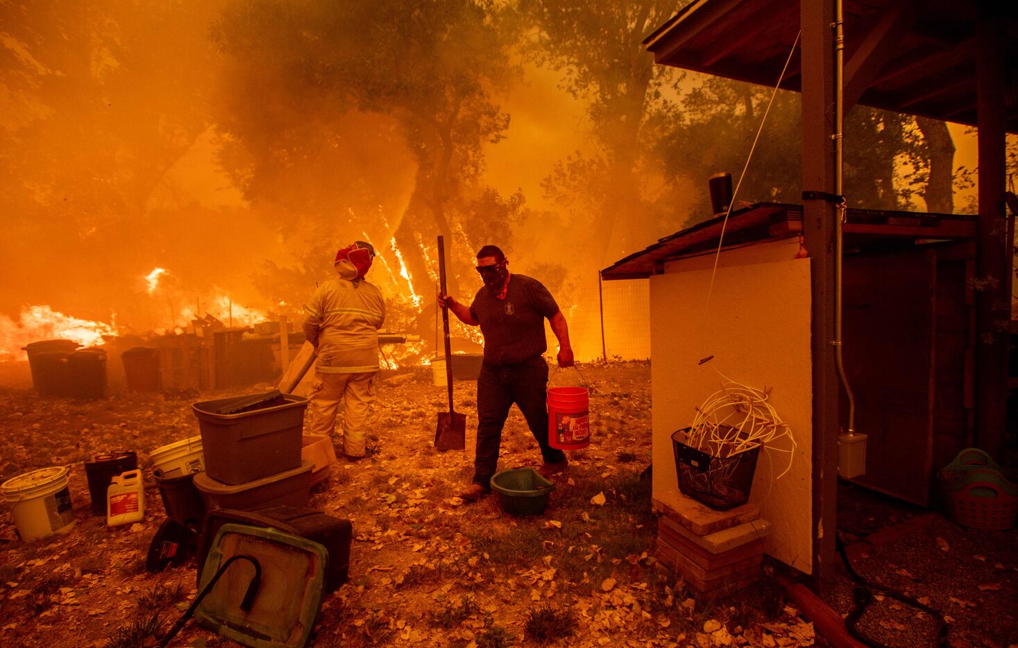 Resident Lane Lawder carries a water bucket while fighting to save his home from the Ranch...