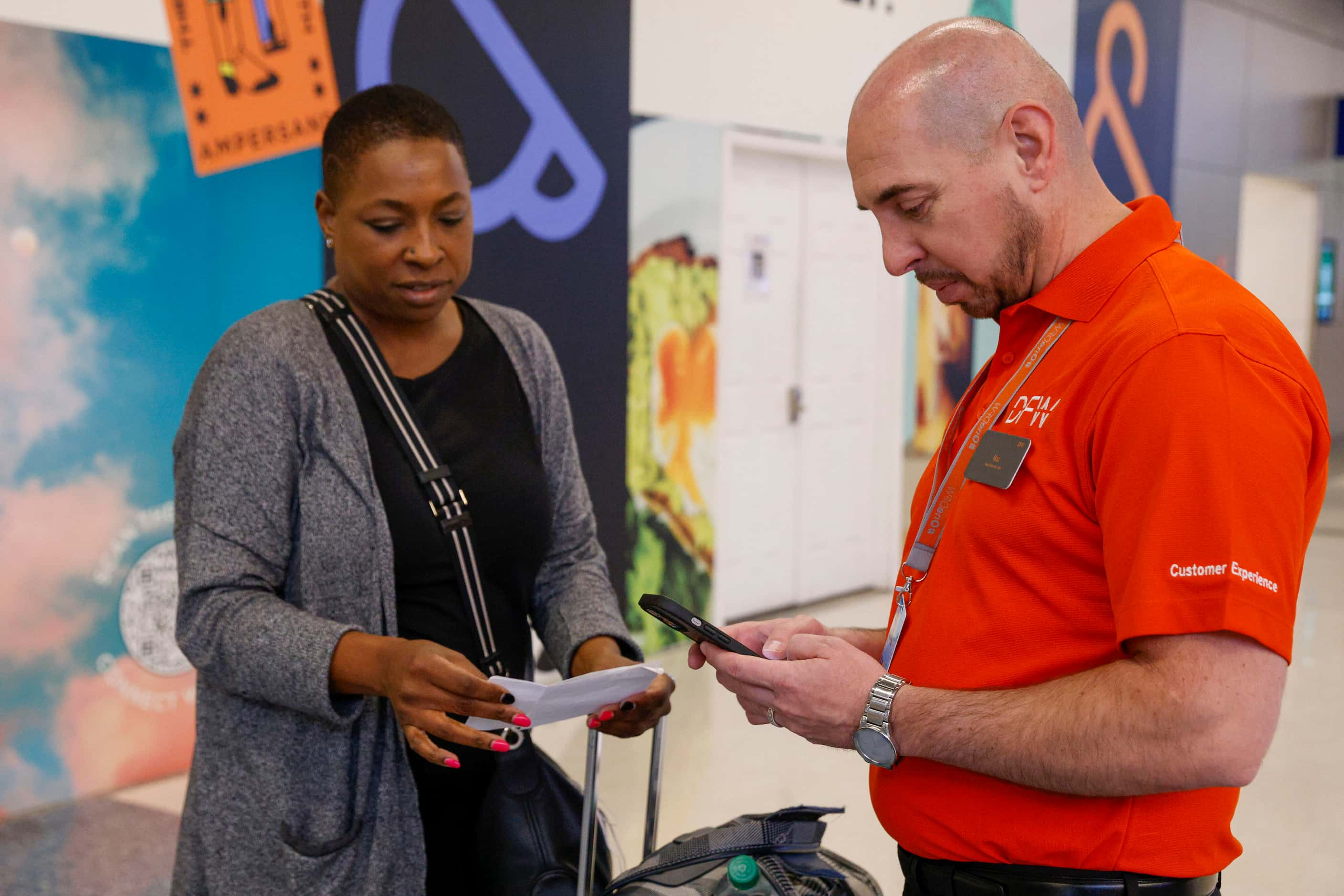 Supervisor of terminal experience Nic Arifi (right) looks up flight information for Veronica...