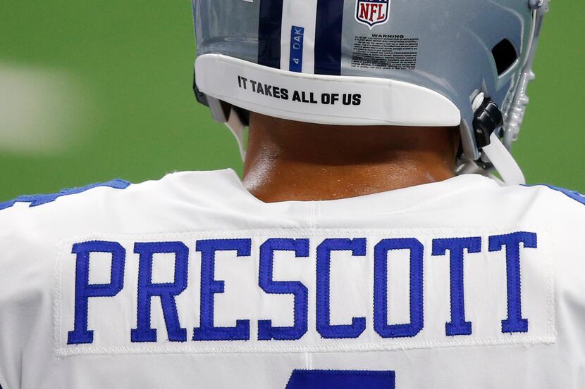 The message "It takes all of us," printed on the back of the helmet of Cowboys quarterback...